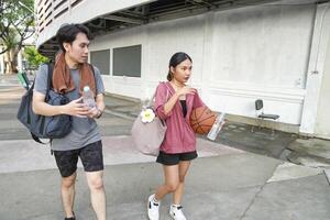 The male and female basketball players practice using the ball in the park court diligently and happily. photo