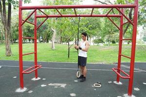 Asian man practicing gymnastics doing gymnastics bar and hoop exercises and stretching and resting for sports. photo