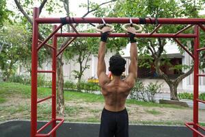 Asian man practicing gymnastics, doing gymnastics bar and hoop exercises and stretching, resting for sports. photo