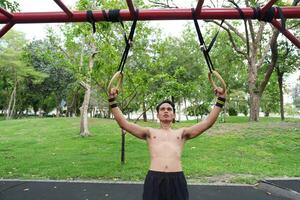 Asian man practicing gymnastics, doing gymnastics bar and hoop exercises and stretching, resting for sports. photo