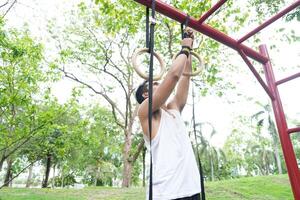 Asian man practicing gymnastics doing gymnastics bar and hoop exercises and stretching and resting for sports. photo