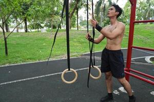 Asian man practicing gymnastics, doing gymnastics bar and hoop exercises and stretching, resting for sports. photo