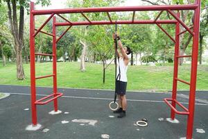 Asian man practicing gymnastics doing gymnastics bar and hoop exercises and stretching and resting for sports. photo
