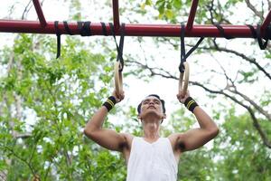 Asian man practicing gymnastics doing gymnastics bar and hoop exercises and stretching and resting for sports. photo