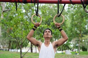 Asian man practicing gymnastics doing gymnastics bar and hoop exercises and stretching and resting for sports. photo