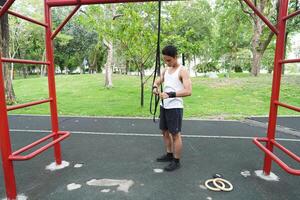 Asian man practicing gymnastics doing gymnastics bar and hoop exercises and stretching and resting for sports. photo