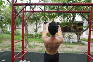 Asian man practicing gymnastics, doing gymnastics bar and hoop exercises and stretching, resting for sports. photo