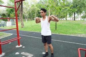 Asian man practicing gymnastics doing gymnastics bar and hoop exercises and stretching and resting for sports. photo