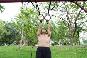 Asian man practicing gymnastics, doing gymnastics bar and hoop exercises and stretching, resting for sports. photo