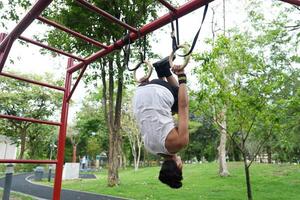 Asian man practicing gymnastics, doing gymnastics bar and hoop exercises and stretching, resting for sports. photo
