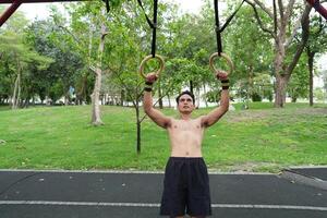Asian man practicing gymnastics, doing gymnastics bar and hoop exercises and stretching, resting for sports. photo