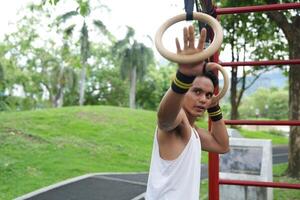 Asian man practicing gymnastics, doing gymnastics bar and hoop exercises and stretching, resting for sports. photo
