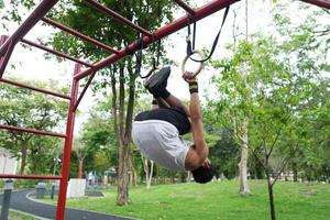Asian man practicing gymnastics, doing gymnastics bar and hoop exercises and stretching, resting for sports. photo