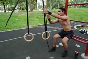 Asian man practicing gymnastics, doing gymnastics bar and hoop exercises and stretching, resting for sports. photo