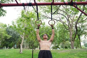 Asian man practicing gymnastics, doing gymnastics bar and hoop exercises and stretching, resting for sports. photo