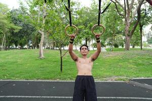 Asian man practicing gymnastics, doing gymnastics bar and hoop exercises and stretching, resting for sports. photo