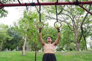 Asian man practicing gymnastics, doing gymnastics bar and hoop exercises and stretching, resting for sports. photo