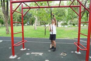Asian man practicing gymnastics doing gymnastics bar and hoop exercises and stretching and resting for sports. photo