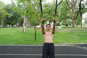Asian man practicing gymnastics, doing gymnastics bar and hoop exercises and stretching, resting for sports. photo