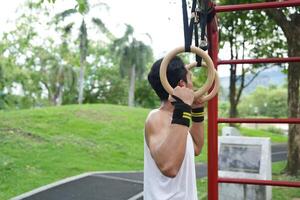 Asian man practicing gymnastics, doing gymnastics bar and hoop exercises and stretching, resting for sports. photo