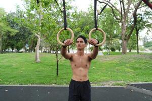 Asian man practicing gymnastics, doing gymnastics bar and hoop exercises and stretching, resting for sports. photo
