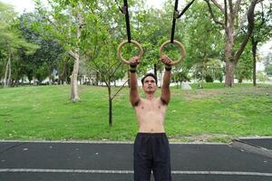 Asian man practicing gymnastics, doing gymnastics bar and hoop exercises and stretching, resting for sports. photo