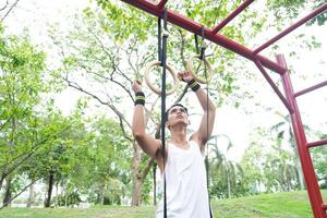 Asian man practicing gymnastics doing gymnastics bar and hoop exercises and stretching and resting for sports. photo