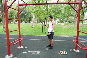 Asian man practicing gymnastics doing gymnastics bar and hoop exercises and stretching and resting for sports. photo