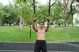 Asian man practicing gymnastics, doing gymnastics bar and hoop exercises and stretching, resting for sports. photo