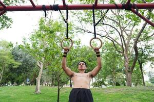 Asian man practicing gymnastics, doing gymnastics bar and hoop exercises and stretching, resting for sports. photo