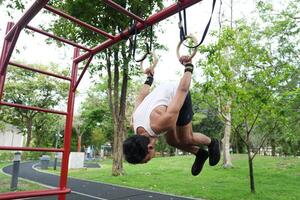 Asian man practicing gymnastics, doing gymnastics bar and hoop exercises and stretching, resting for sports. photo