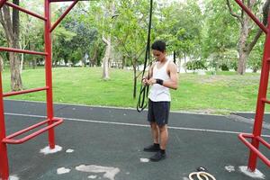 Asian man practicing gymnastics doing gymnastics bar and hoop exercises and stretching and resting for sports. photo