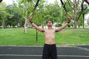 Asian man practicing gymnastics, doing gymnastics bar and hoop exercises and stretching, resting for sports. photo