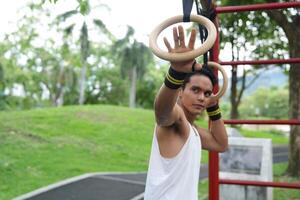 Asian man practicing gymnastics, doing gymnastics bar and hoop exercises and stretching, resting for sports. photo