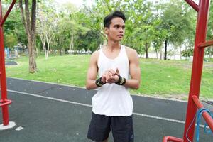 Asian man practicing gymnastics doing gymnastics bar and hoop exercises and stretching and resting for sports. photo