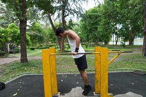 Asian man practicing gymnastics, doing gymnastics bar and hoop exercises and stretching, resting for sports. photo