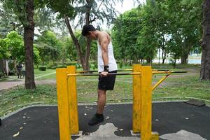Asian man practicing gymnastics, doing gymnastics bar and hoop exercises and stretching, resting for sports. photo
