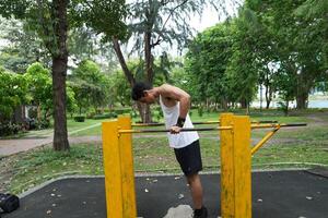 Asian man practicing gymnastics, doing gymnastics bar and hoop exercises and stretching, resting for sports. photo