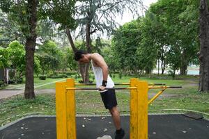 Asian man practicing gymnastics, doing gymnastics bar and hoop exercises and stretching, resting for sports. photo