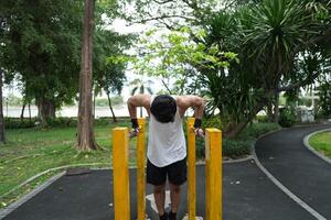 Asian man practicing gymnastics, doing gymnastics bar and hoop exercises and stretching, resting for sports. photo