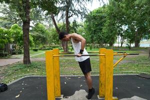 Asian man practicing gymnastics, doing gymnastics bar and hoop exercises and stretching, resting for sports. photo