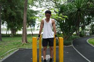 Asian man practicing gymnastics, doing gymnastics bar and hoop exercises and stretching, resting for sports. photo