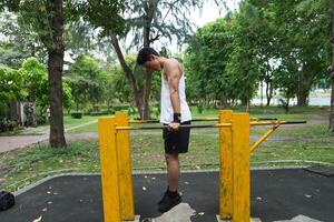 Asian man practicing gymnastics, doing gymnastics bar and hoop exercises and stretching, resting for sports. photo
