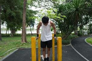 Asian man practicing gymnastics, doing gymnastics bar and hoop exercises and stretching, resting for sports. photo