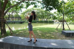 Asian woman dancing in the middle of a park photo