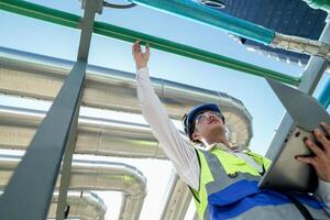 Industrial engineer adjusting pipeline valve with radio communication on construction site. Engineer on urban construction site using radio to coordinate with team on a sunny industrial rooftop. photo