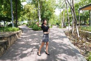 Asian woman dancing in the middle of a park photo