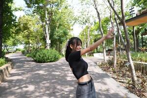 Asian woman dancing in the middle of a park photo
