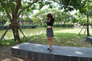 Asian woman dancing in the middle of a park photo