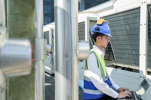 Industrial engineer adjusting pipeline valve with radio communication on construction site. Engineer on urban construction site using radio to coordinate with team on a sunny industrial rooftop. photo